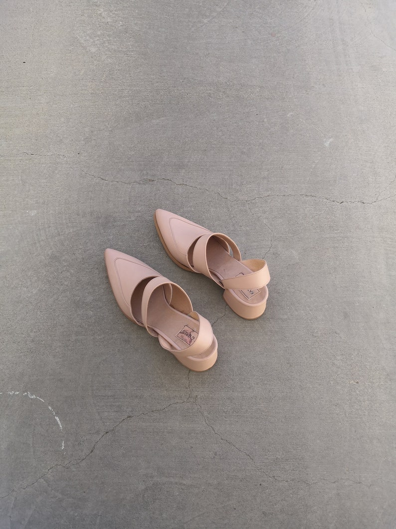 May include: A pair of light brown leather heeled sandals with ankle straps. The sandals have a pointed toe and a chunky heel.