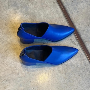May include: A pair of blue leather heeled shoes with a pointed toe and a zipper on the back.