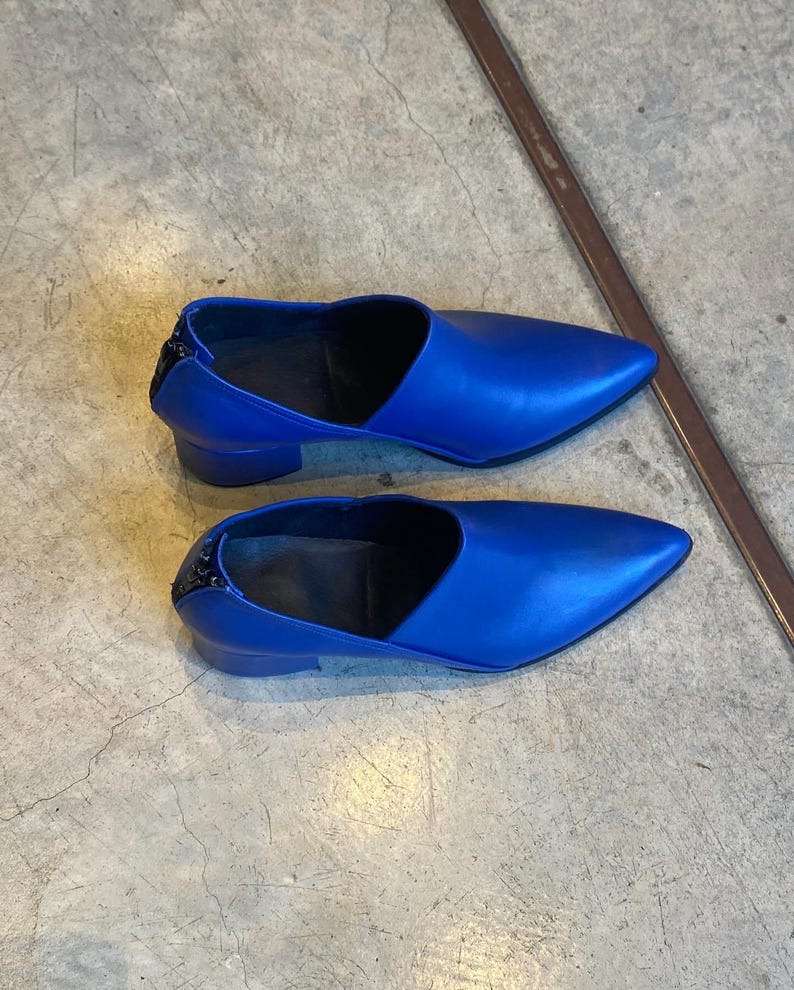 May include: A pair of blue leather heeled shoes with a pointed toe and a zipper on the back.