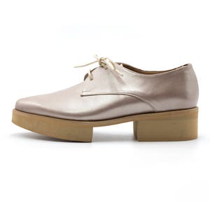 May include: A pair of light pink leather lace-up shoes with a chunky platform sole.