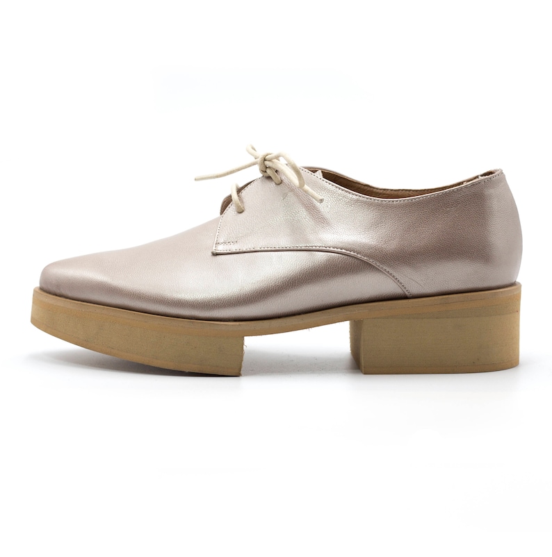 May include: A pair of light pink leather lace-up shoes with a chunky platform sole.
