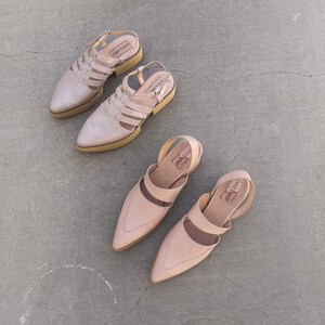 May include: Three pairs of light pink leather sandals with ankle straps. The sandals have a pointed toe and a low heel. The brand name "LAZY" is visible on the straps.