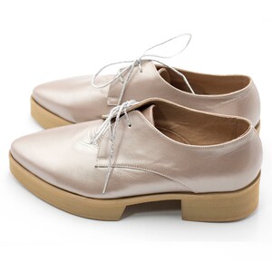 May include: A pair of light pink leather lace-up shoes with a pointed toe and a thick platform sole.