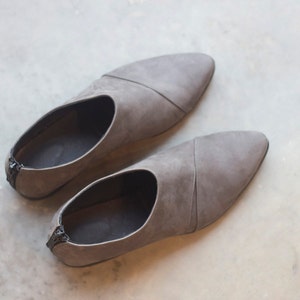 May include: A pair of gray suede slip-on shoes with pointed toes.