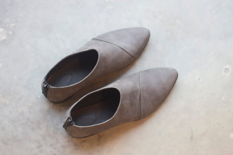 May include: A pair of gray suede slip-on shoes with pointed toes.