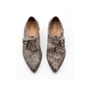 May include: A pair of brown and white pointed-toe shoes with a buckle closure.