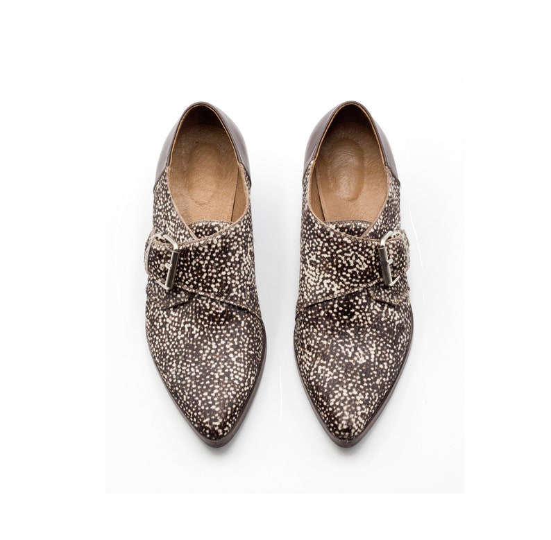 May include: A pair of brown and white pointed-toe shoes with a buckle closure.