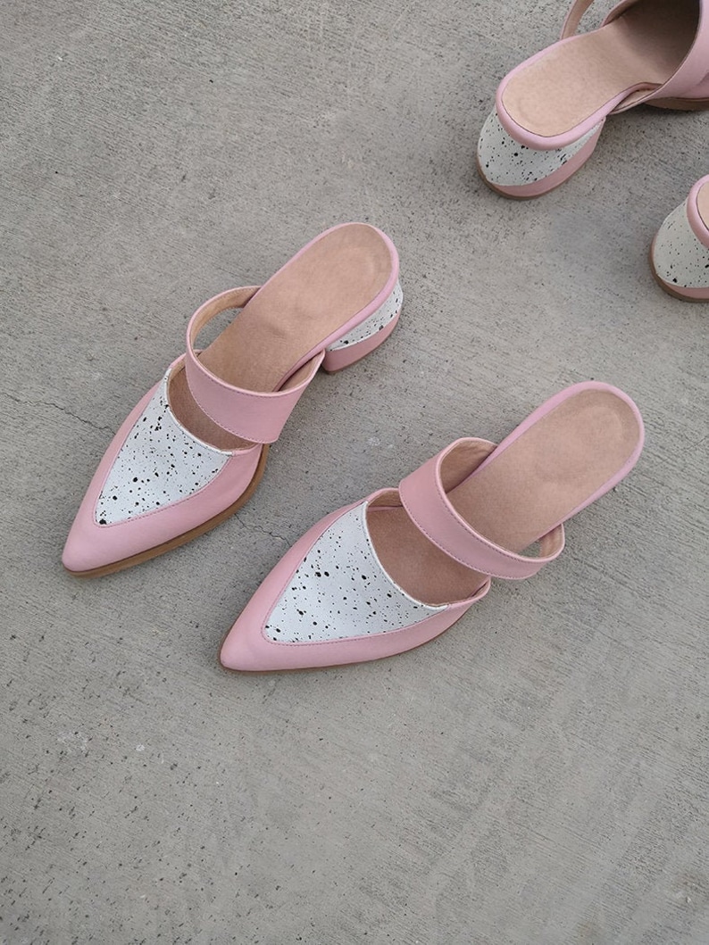 May include: Two pairs of pink and white heeled mules with a speckled pattern. The shoes have a pointed toe and a chunky heel.