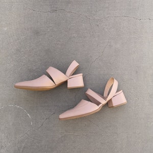 May include: A pair of light pink heeled sandals with a cut-out design and ankle strap.