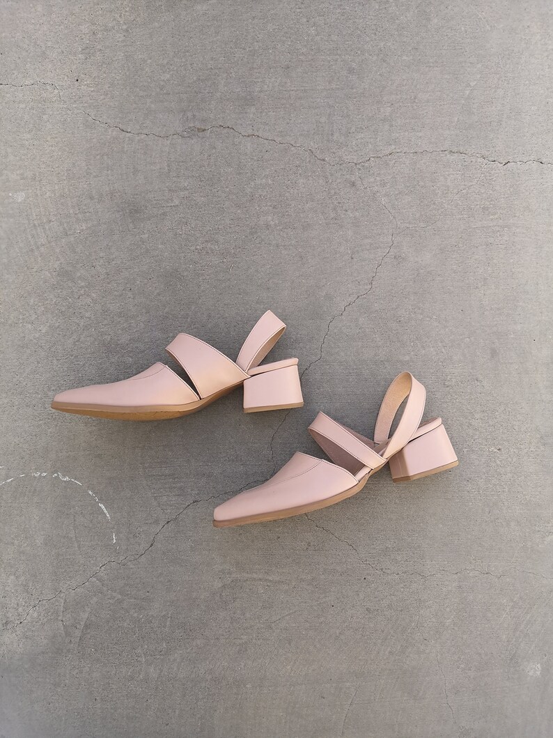 May include: A pair of light pink heeled sandals with a cut-out design and ankle strap.
