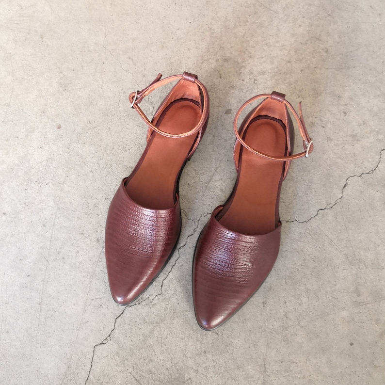 May include: A pair of brown leather ankle strap sandals with pointed toes.