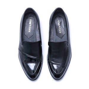 May include: A pair of black leather loafers with a patent leather toe. The loafers have a slip-on design and feature the text "KATZ & BROS" on the insole.