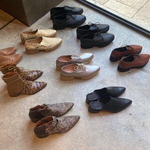 May include: A variety of shoes and boots in different styles and colors, including brown leather boots, black leather shoes, and white canvas shoes.