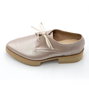 May include: A pair of light pink leather lace-up shoes with a thick platform sole.