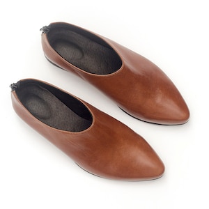 May include: A pair of brown leather slip-on shoes with pointed toes.