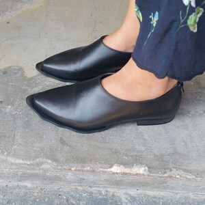 May include: A pair of black leather pointed-toe flats with a low heel.