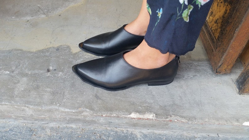 May include: A pair of black leather pointed-toe flats with a low heel.