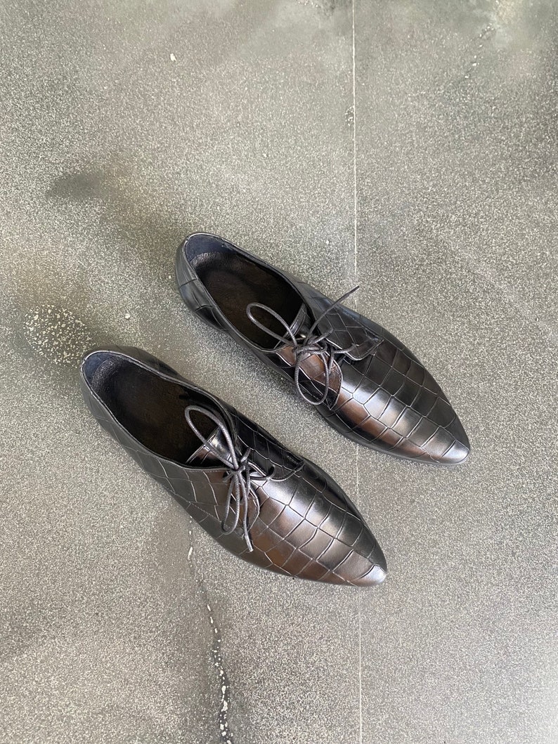 May include: A pair of black leather oxfords with a crocodile-embossed pattern and lace-up closures.