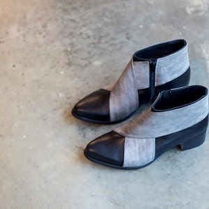 May include: A pair of gray and black ankle boots with a pointed toe and a zipper on the side.
