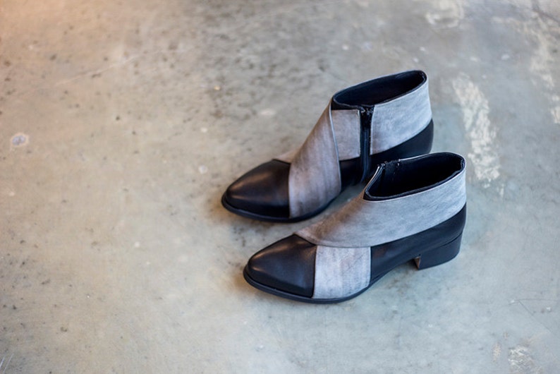 May include: A pair of gray and black ankle boots with a pointed toe and a zipper on the side.