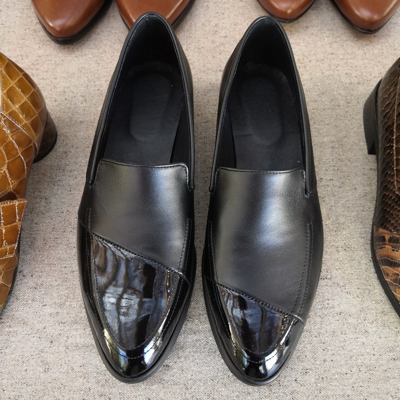 May include: A pair of black leather loafers with a pointed toe and a patent leather trim. The loafers have a slip-on design and are perfect for casual wear.