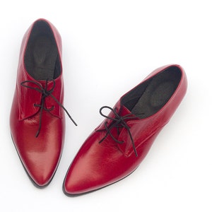 May include: A pair of red leather lace-up shoes with pointed toes.