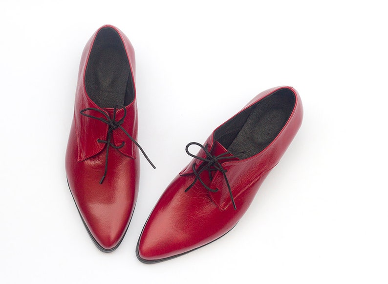 May include: A pair of red leather lace-up shoes with pointed toes.
