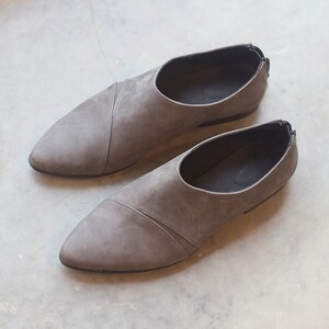 May include: A pair of gray suede slip-on shoes with pointed toes.