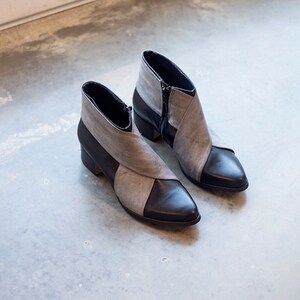 May include: A pair of gray and black ankle boots with pointed toes. The boots have a zipper on the side and a contrasting color design.
