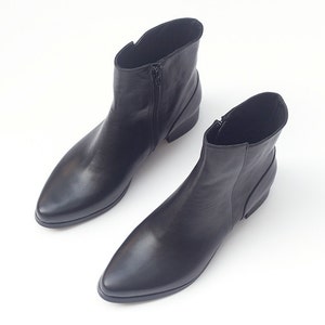 May include: A pair of black leather ankle boots with pointed toes and zipper closures.