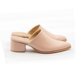 May include: A pair of blush pink leather heeled mules with a pointed toe and a block heel.