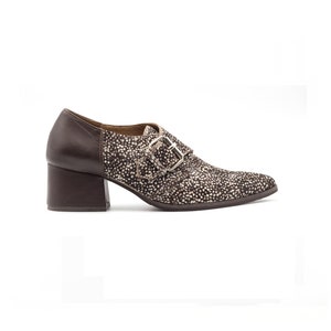 May include: Brown leather heeled shoes with a buckle closure and a spotted pattern on the upper part of the shoe.