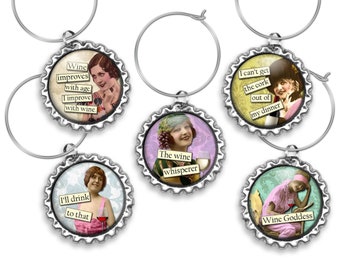 May include: Six silver wine glass charms with colorful images and humorous sayings. The charms feature vintage-style illustrations of women and include sayings like "Wine improves with age, I improve with wine." and "Wine Goddess."