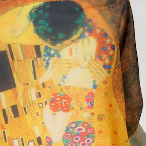 May include: A close-up of a painting depicting a couple embracing. The woman is wearing a white dress with floral details and the man is wearing a black suit. The background is a gold and yellow pattern with circles and squares.