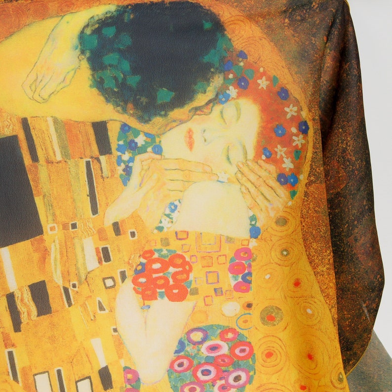 May include: A close-up of a painting depicting a couple embracing. The woman is wearing a white dress with floral details and the man is wearing a black suit. The background is a gold and yellow pattern with circles and squares.