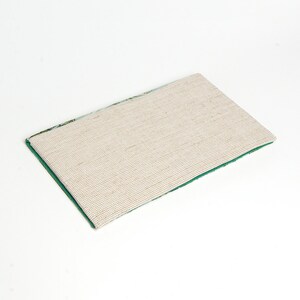May include: A green and white patterned rug with a beige non-slip backing. The rug is rectangular and has a fringed edge.