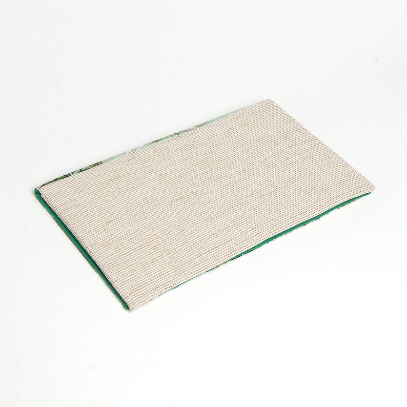 May include: A green and white patterned rug with a beige non-slip backing. The rug is rectangular and has a fringed edge.