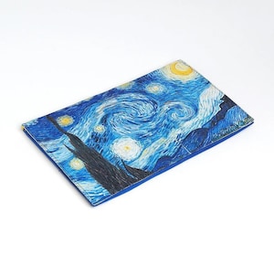 Puede incluir: Una cartera azul con una impresi&oacute;n de La Noche Estrellada de Van Gogh.