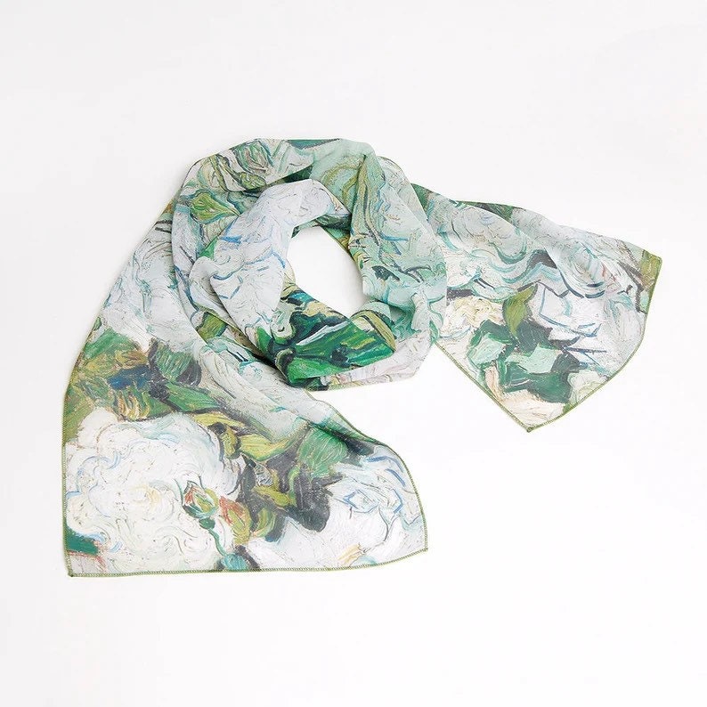May include: A white and green silk scarf with a floral print. The print is reminiscent of a painting with brushstrokes and a painterly style.