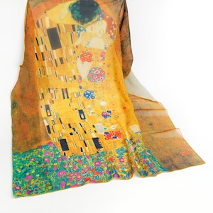May include: A yellow silk scarf with a colorful print of Gustav Klimt's "The Kiss" painting. The scarf features a couple embracing in a golden mosaic pattern with a floral border.