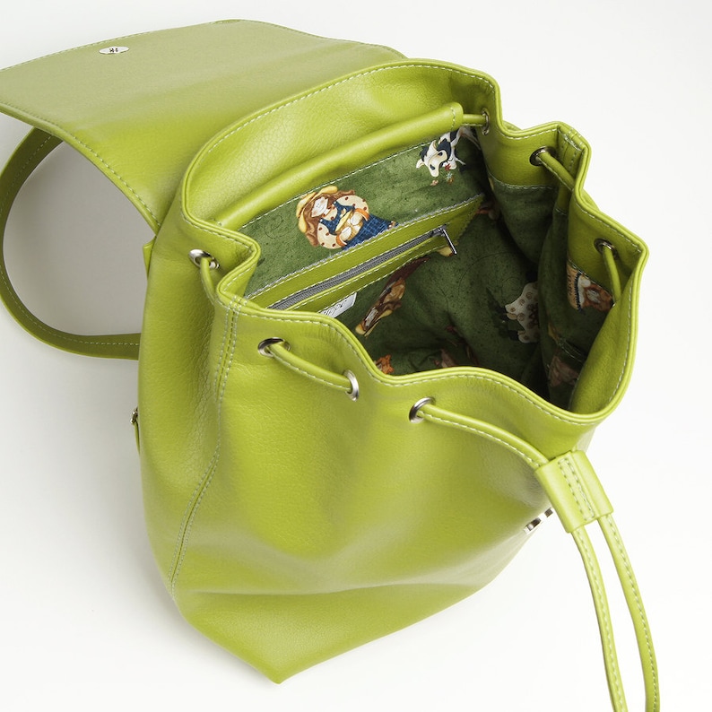 May include: A lime green leather backpack with a drawstring closure and a small zippered pocket on the front. The inside of the backpack is lined with a green and white floral print.