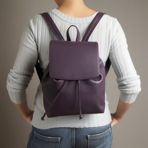 May include: A purple faux leather backpack with a drawstring closure and adjustable straps.