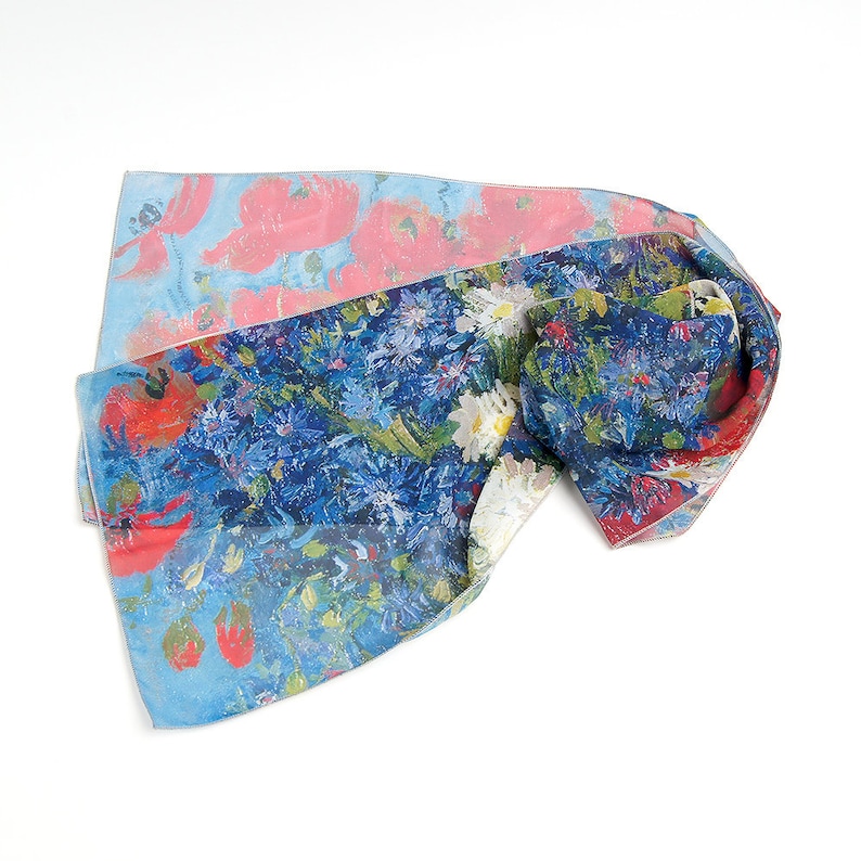 May include: A blue and pink silk scarf with a floral print. The scarf features a variety of flowers, including poppies, daisies, and cornflowers. The scarf is folded and tied in a knot.