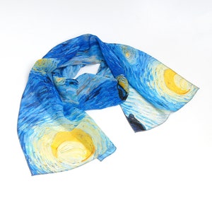 Puede incluir: Una bufanda de seda azul con un dise&ntilde;o impreso de la pintura "La noche estrellada" de Vincent van Gogh. La bufanda presenta estrellas amarillas giratorias y una luna creciente sobre un fondo azul.
