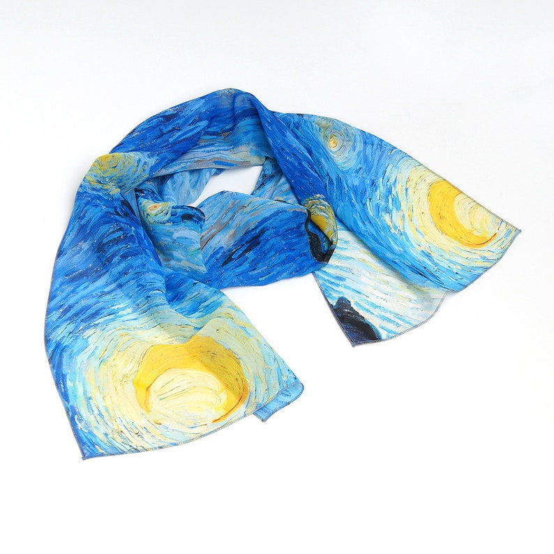 Puede incluir: Una bufanda de seda azul con un dise&ntilde;o impreso de la pintura "La noche estrellada" de Vincent van Gogh. La bufanda presenta estrellas amarillas giratorias y una luna creciente sobre un fondo azul.