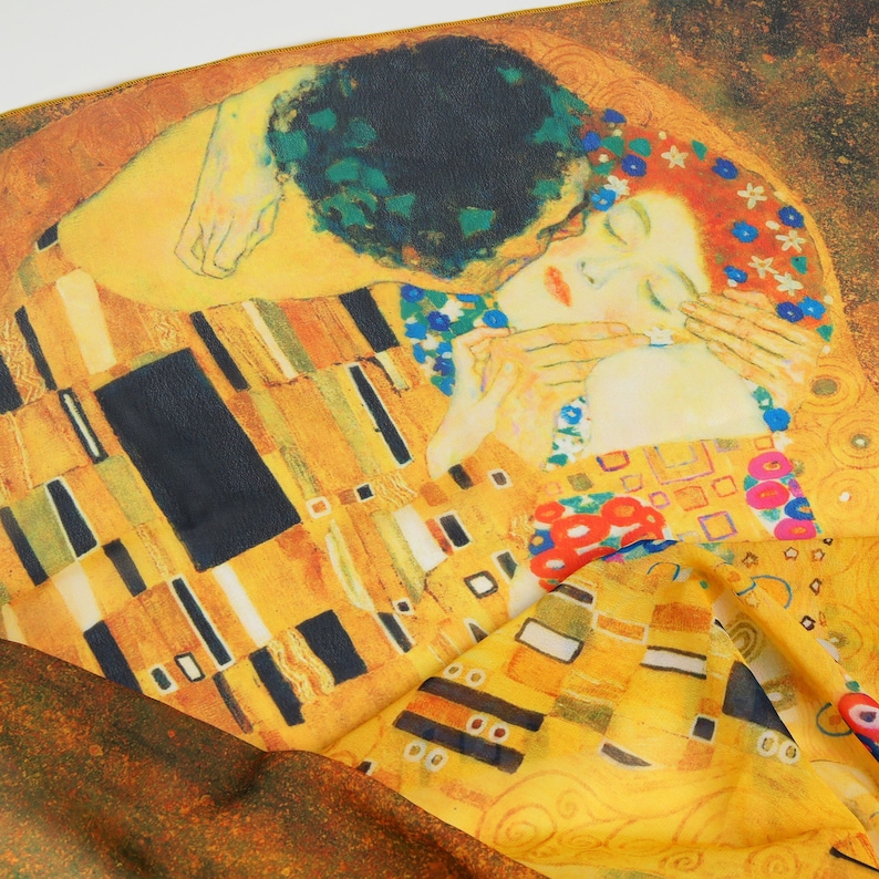 May include: A close-up of a yellow, gold, and black patterned fabric with a painting of two people embracing. The painting is a reproduction of Gustav Klimt's "The Kiss".