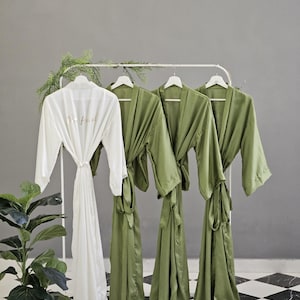 a collection of green and white robes hanging on a rack, with a potted plant in the foreground.