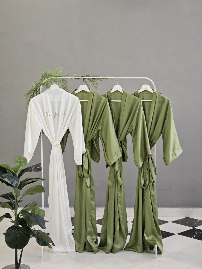 a collection of green and white robes hanging on a rack, with a potted plant in the foreground.