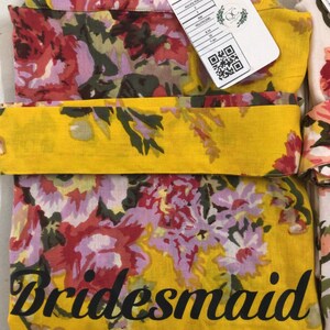 a yellow scarf with flowers and a tag on it