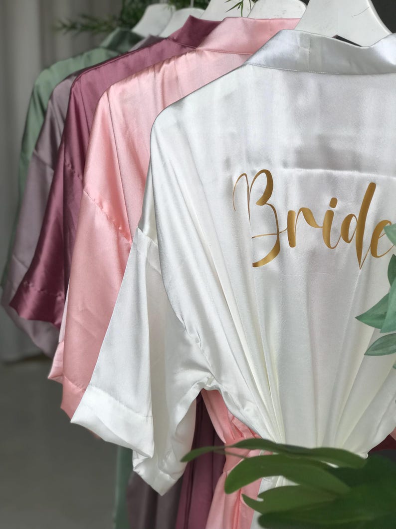 A row of colorful satin robes with the word "Bride" printed on the back.